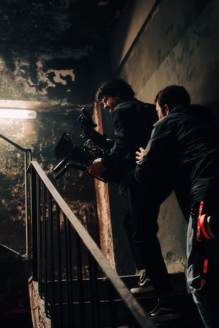 Men filming in an abandoned stairwell, capturing dramatic scene.